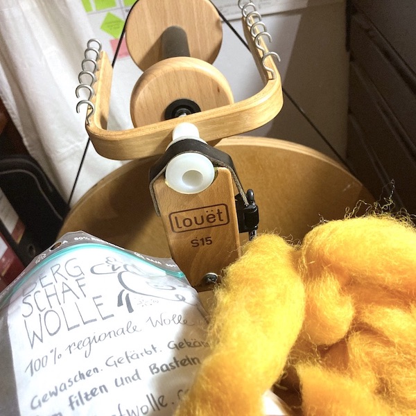 Spinnrad und gelb gefärbte Wolle vom Bergschaf. 